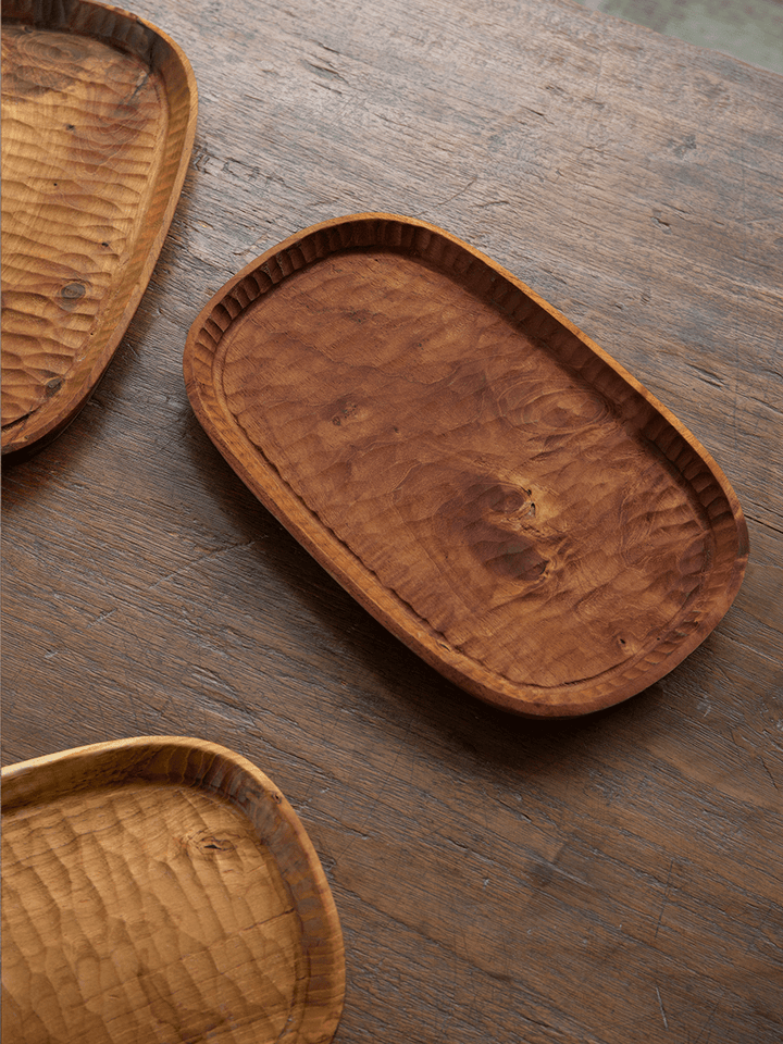 Elegant handcrafted teak wood serving trays on a rustic wooden table.