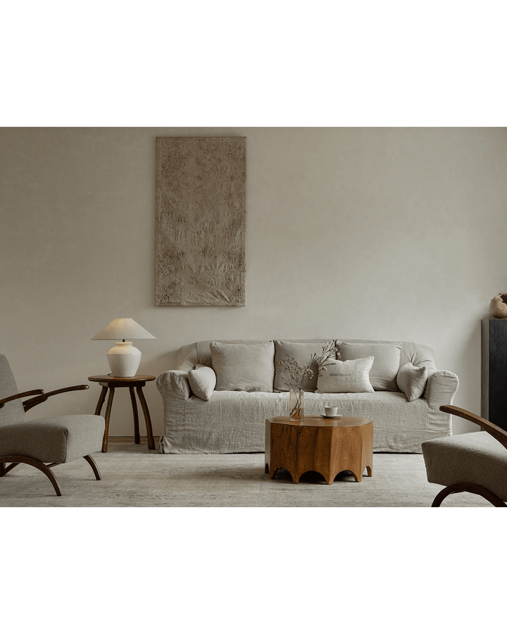 Decagon Side Table in warm wood finish beside a cozy sofa and stylish chairs.