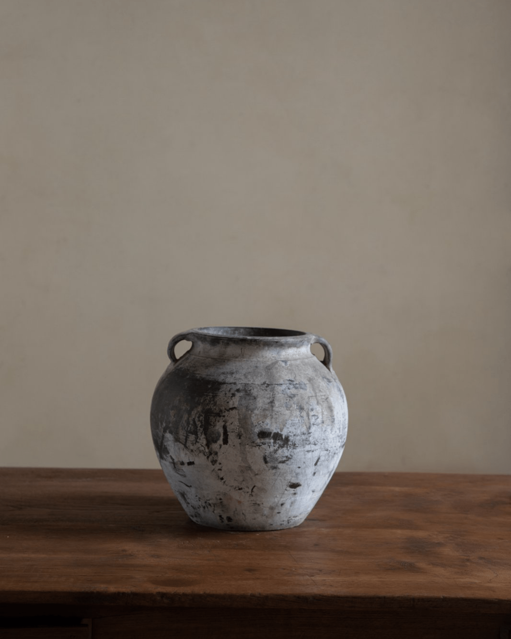 Vintage clay pot with textured gray finish, on a wooden table. Perfect for home decor.