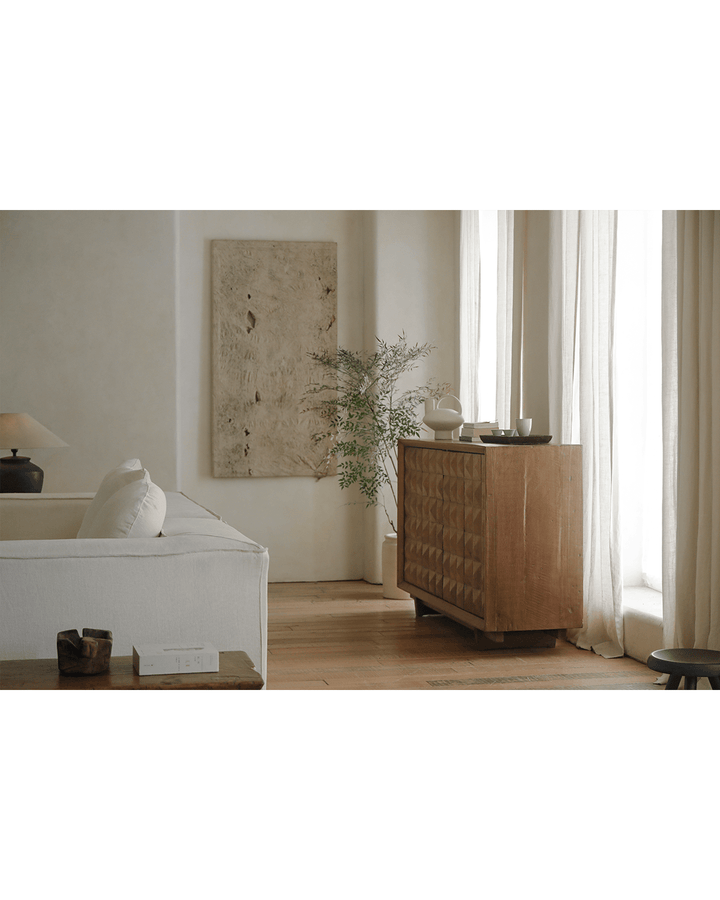 Bumpy sideboard in bright living room with lamp and decorative plant.