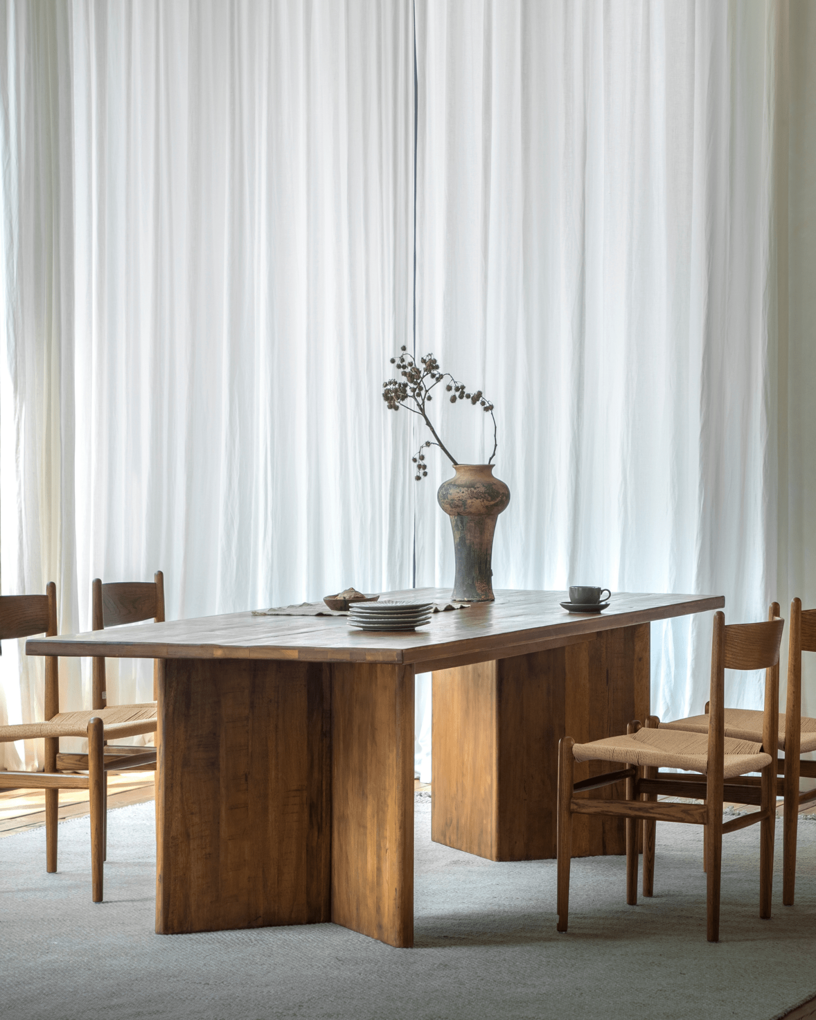Zephyr Dining Table in aged wood, minimalist design, with matching woven chairs.