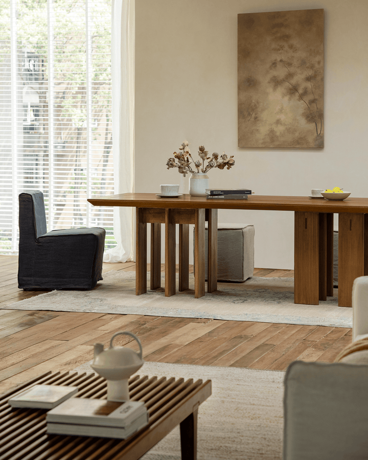 Teak dining table with minimalist decor, chairs, and soft sunlight in a modern interior.