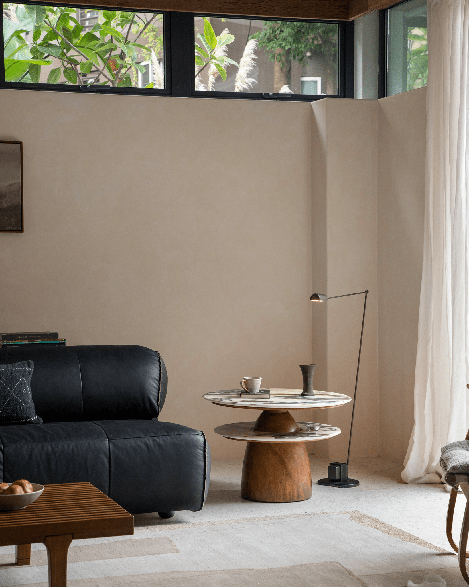 Dorothy Side Table in living room setting, featuring crystal stone top, rain wood base, with elegant black leather sofa