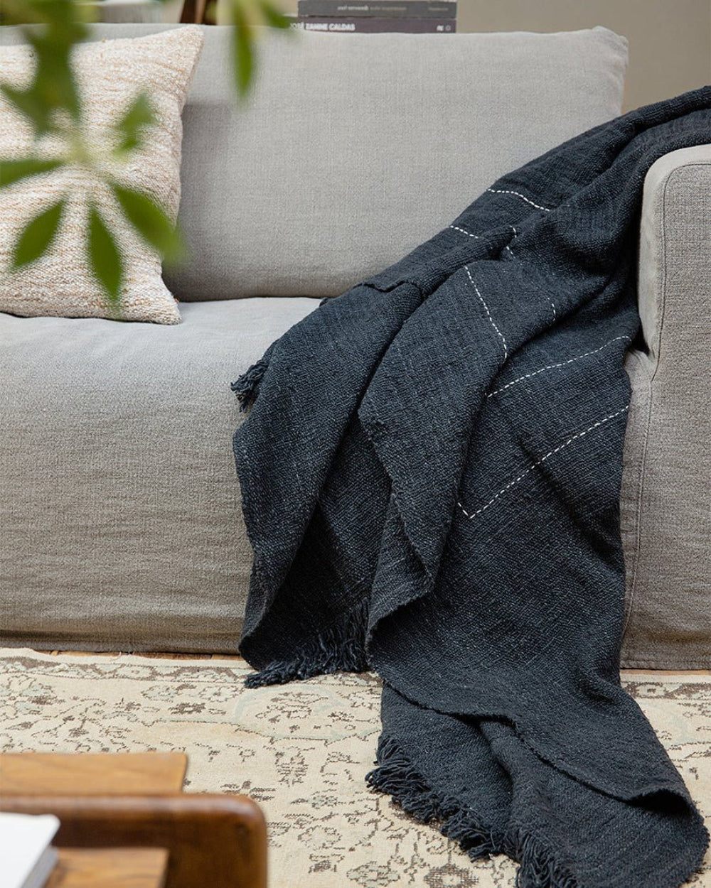 Dark gray cotton blanket on a sofa with white stitching; Cotton Blanket