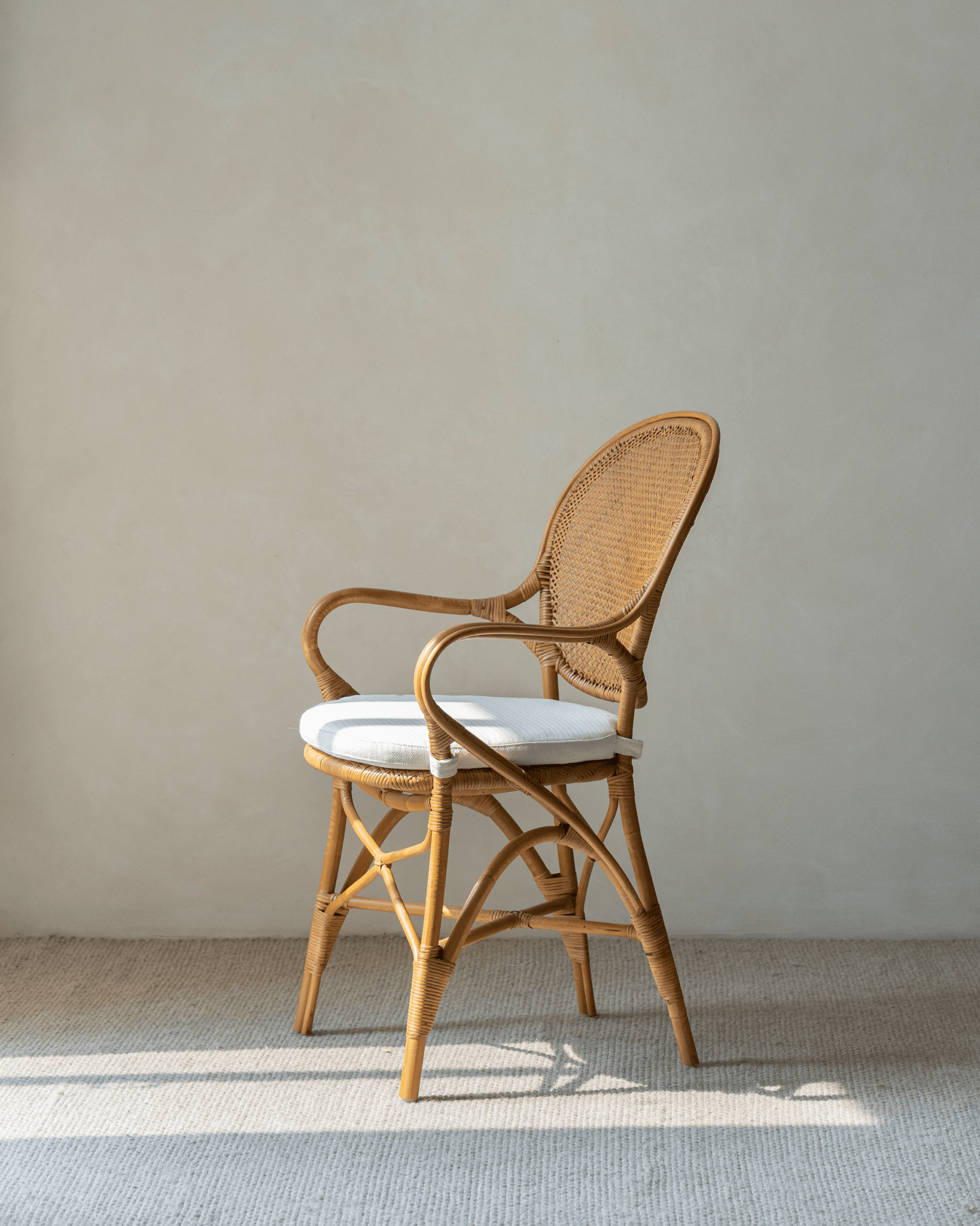 Areca Rattan Chair with white cushion, natural rattan frame, and armrests. Natural comfort design.