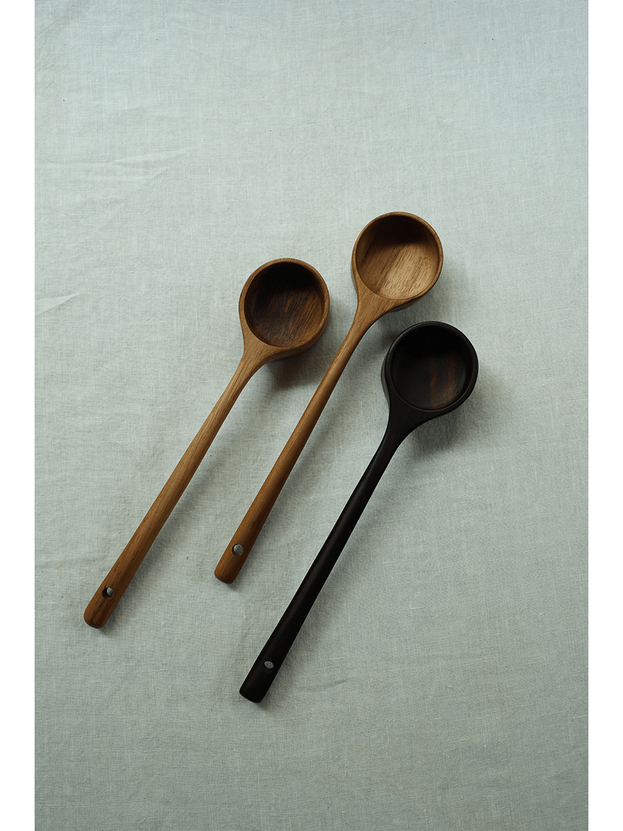 Teak coffee spoons in different wood tones displayed on a linen surface, perfect for coffee and serving.
