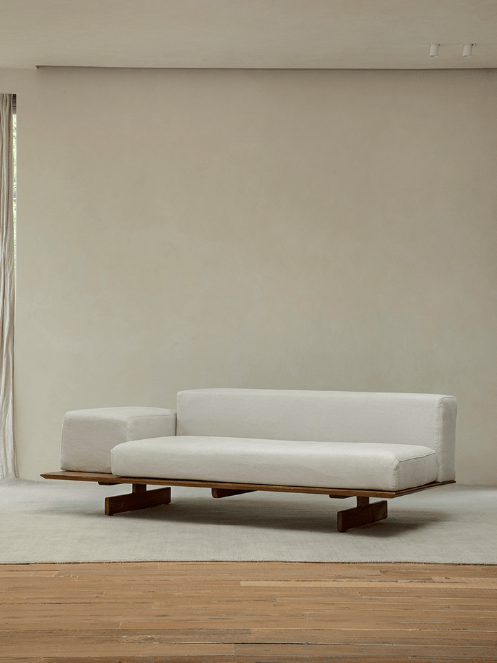 Minimalist linen modular sofa with teak base in neutral-toned interior.