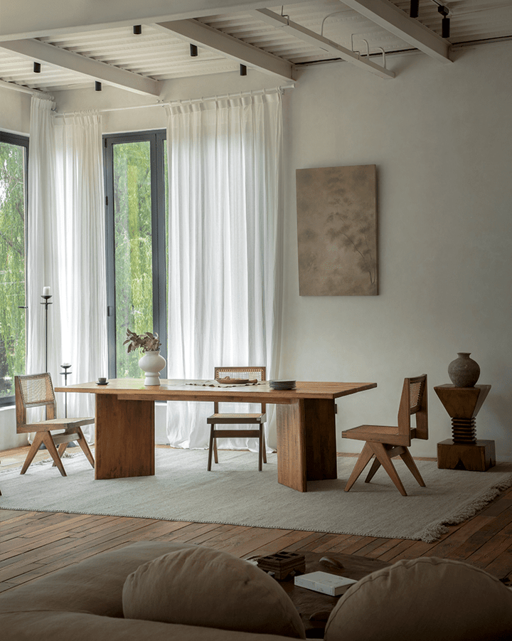 Zephyr dining table with wooden chairs and decorative pieces in a bright, airy space