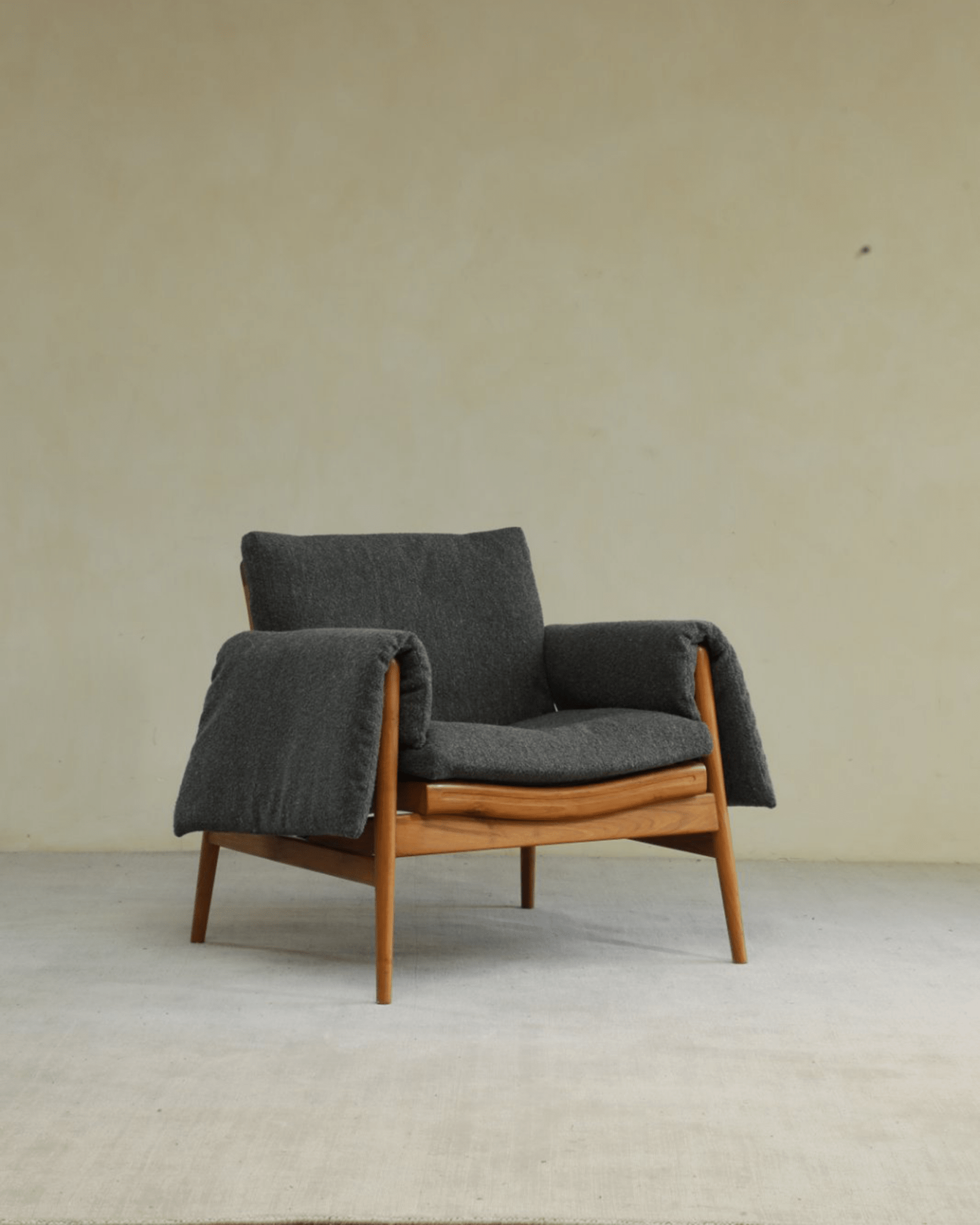 Teak wood garden lounge chair with dark gray cushion and blanket, perfect for indoor and outdoor use