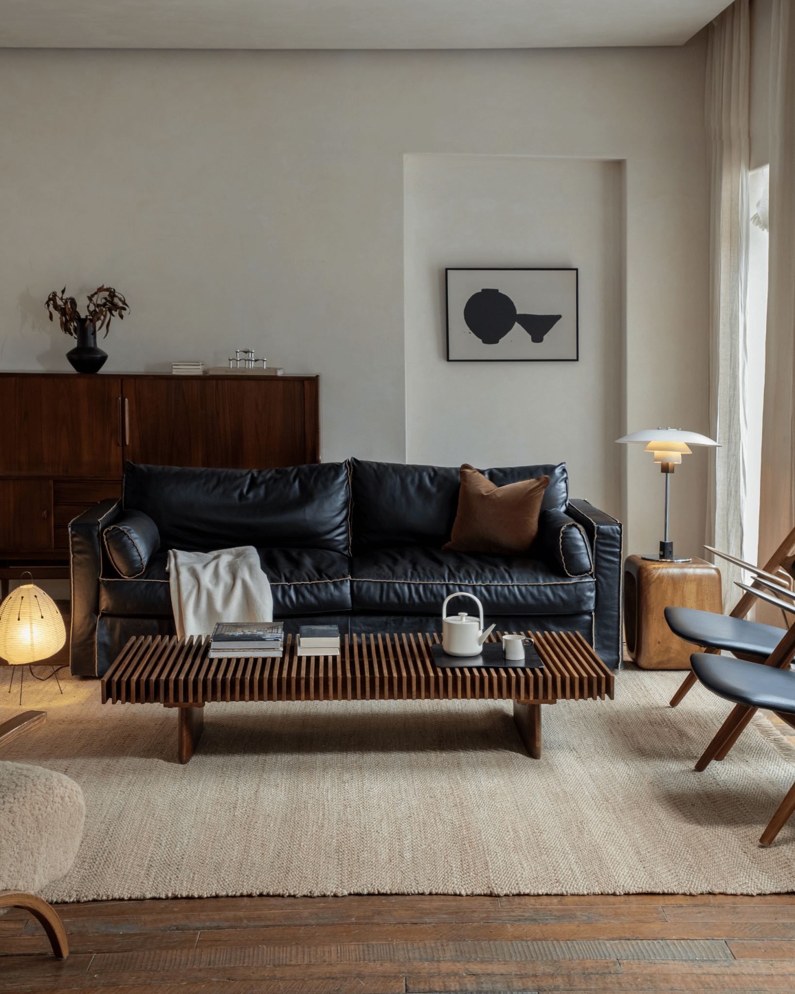 Riva Coffee Table in a modern organic living room setting with black leather sofa and teak wood coffee table