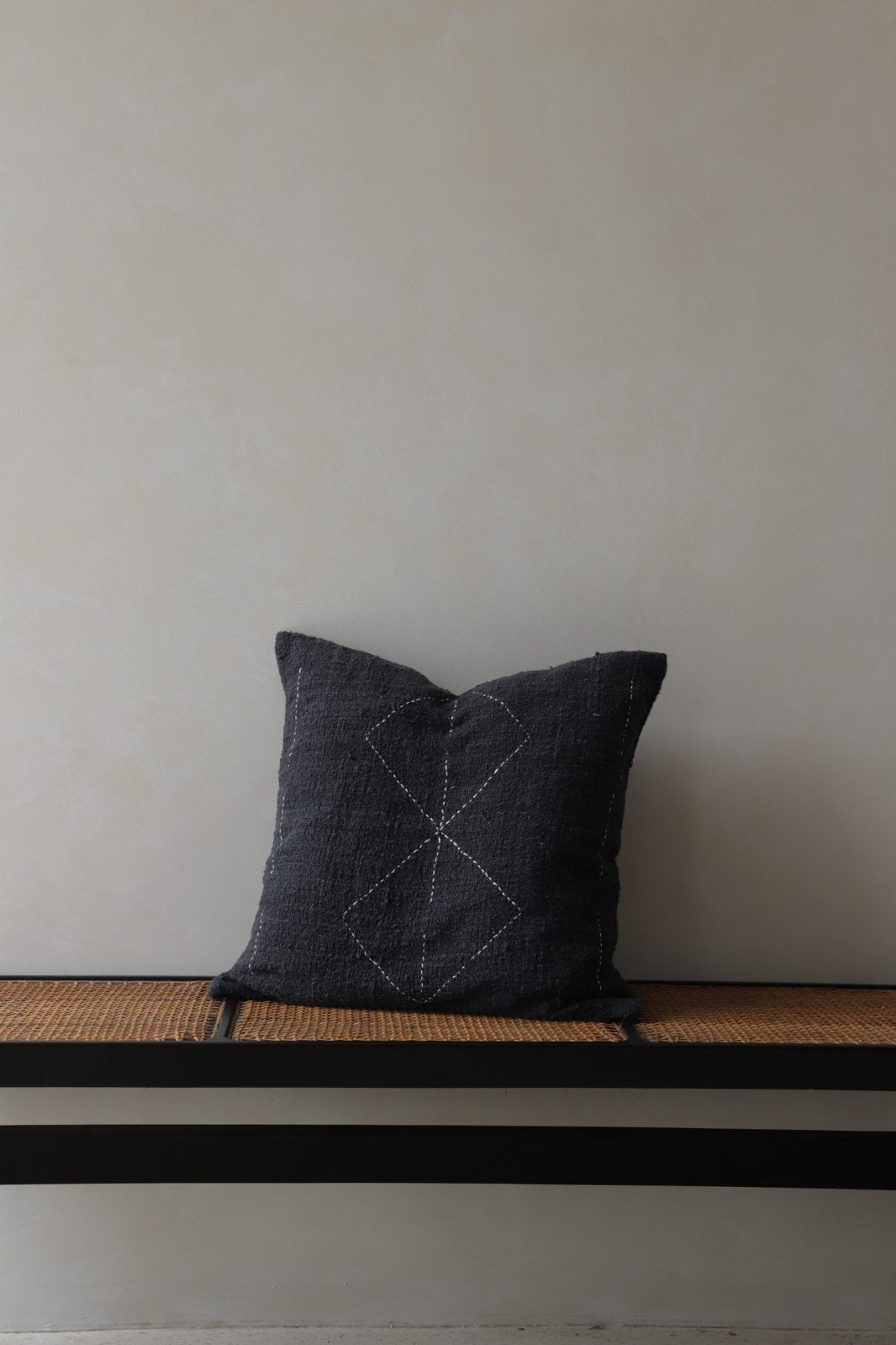 Dark gray cotton pillow with stitched geometric design on a bench, cotton pillow