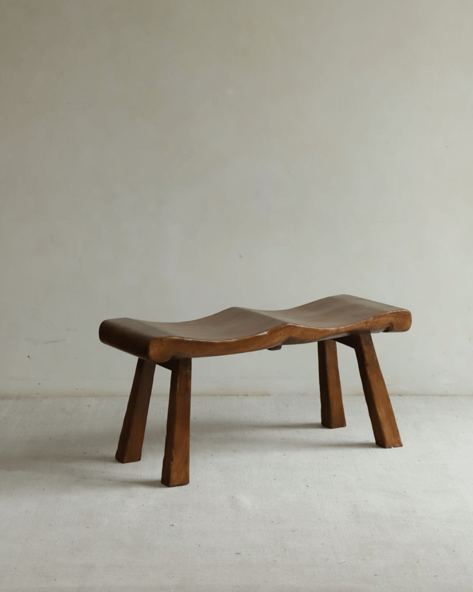 Tildes Bench made of solid wood, brown color, curved seat and sturdy legs.