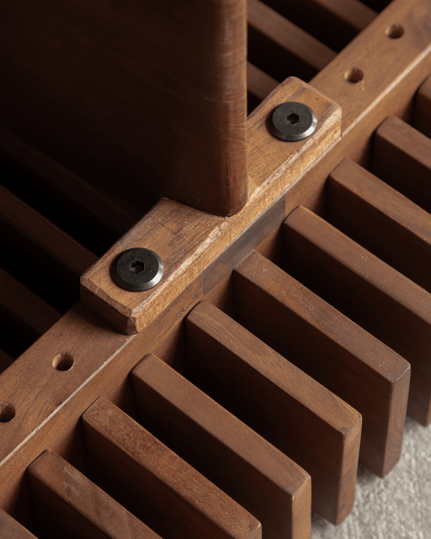 Riva Coffee Table close-up: solid teak slatted wood construction, showing a joint with dark hardware, organic design.