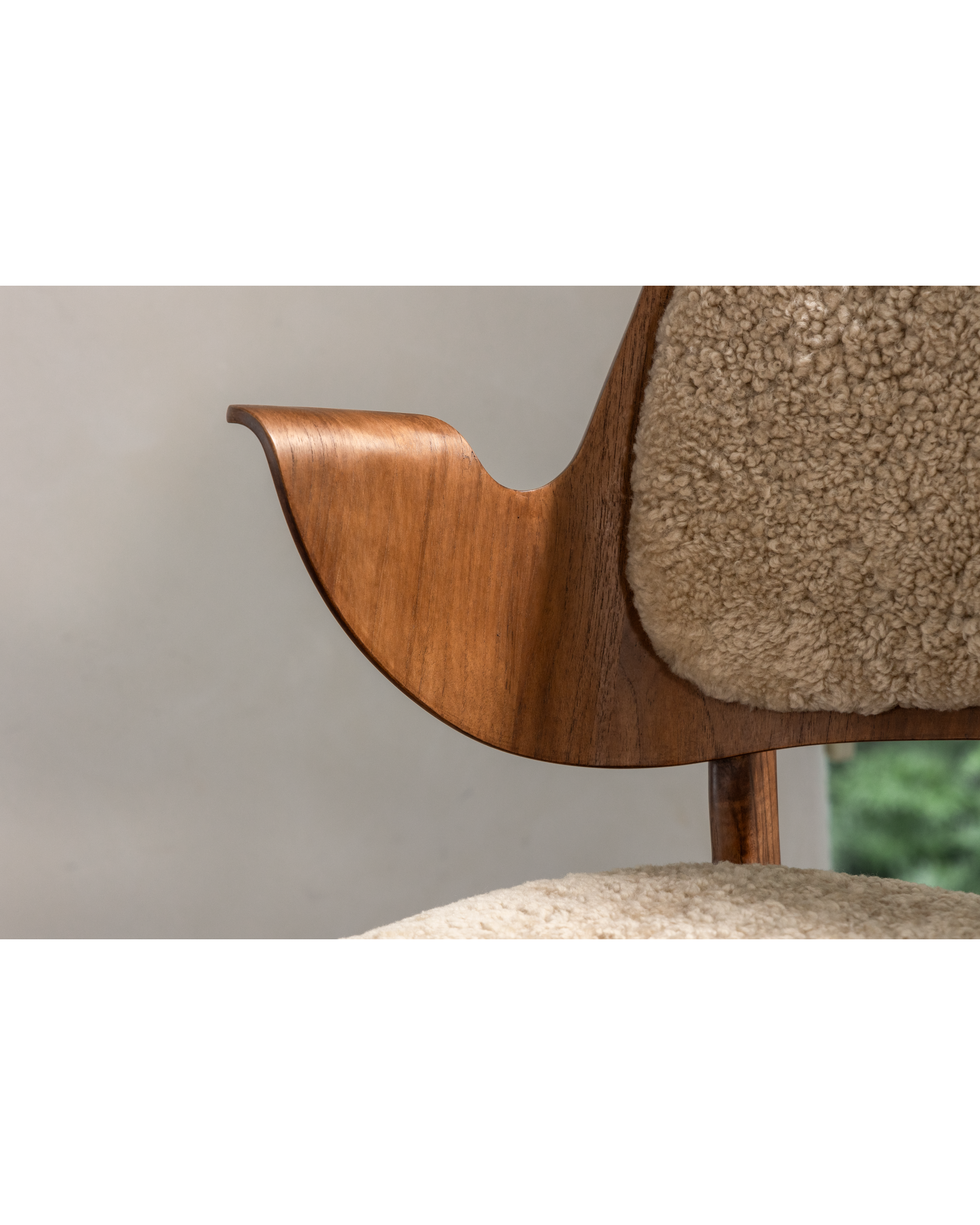 Maren Chair with curved teak wood armrest and plush beige lambswool upholstery.