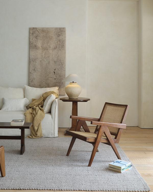 Chandigarh Easy Chair in carbonized black beside natural linen sofa