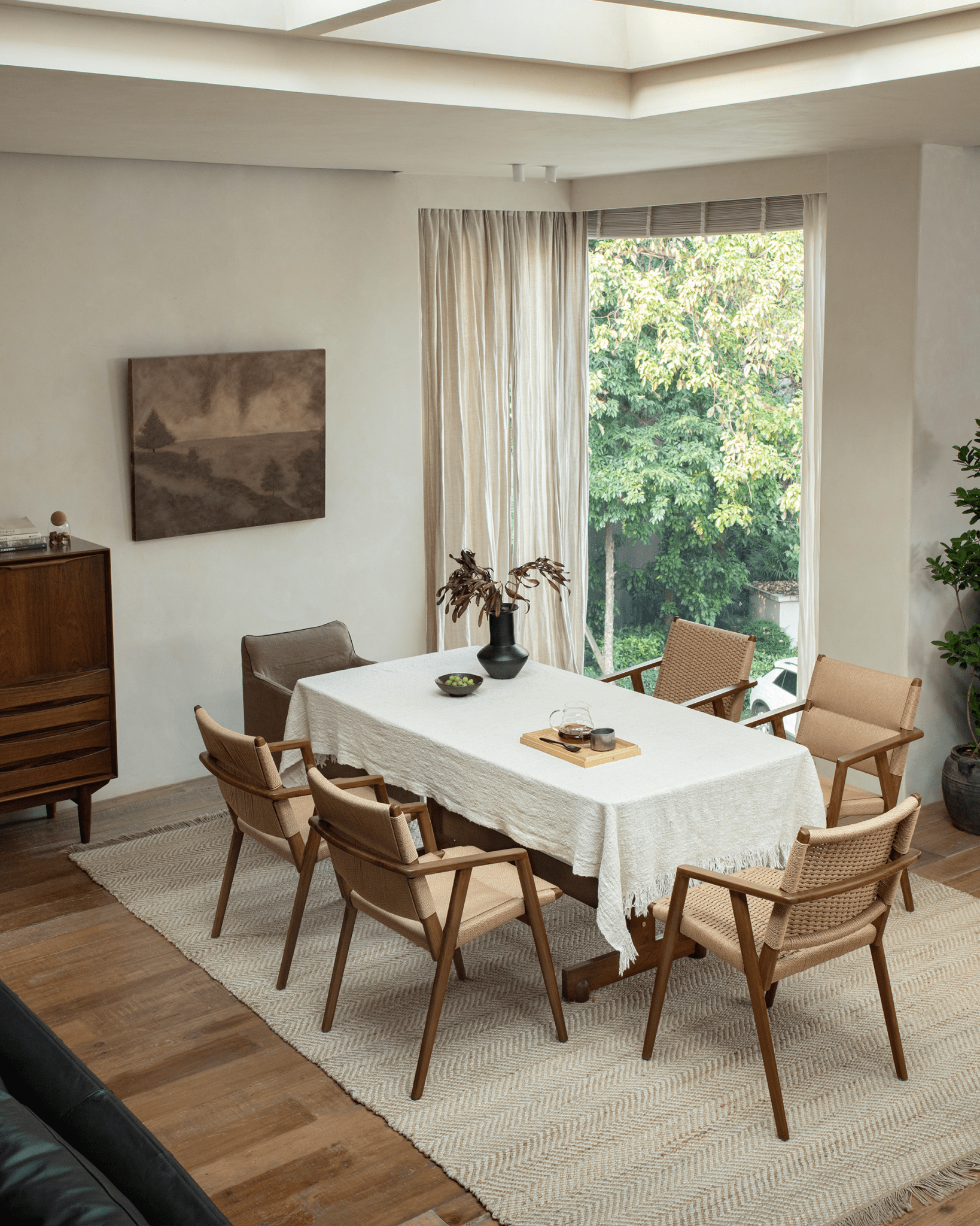Louisa Chair in dining room setting, showcasing teak frame, woven seat, and Mid-Century Modern design.