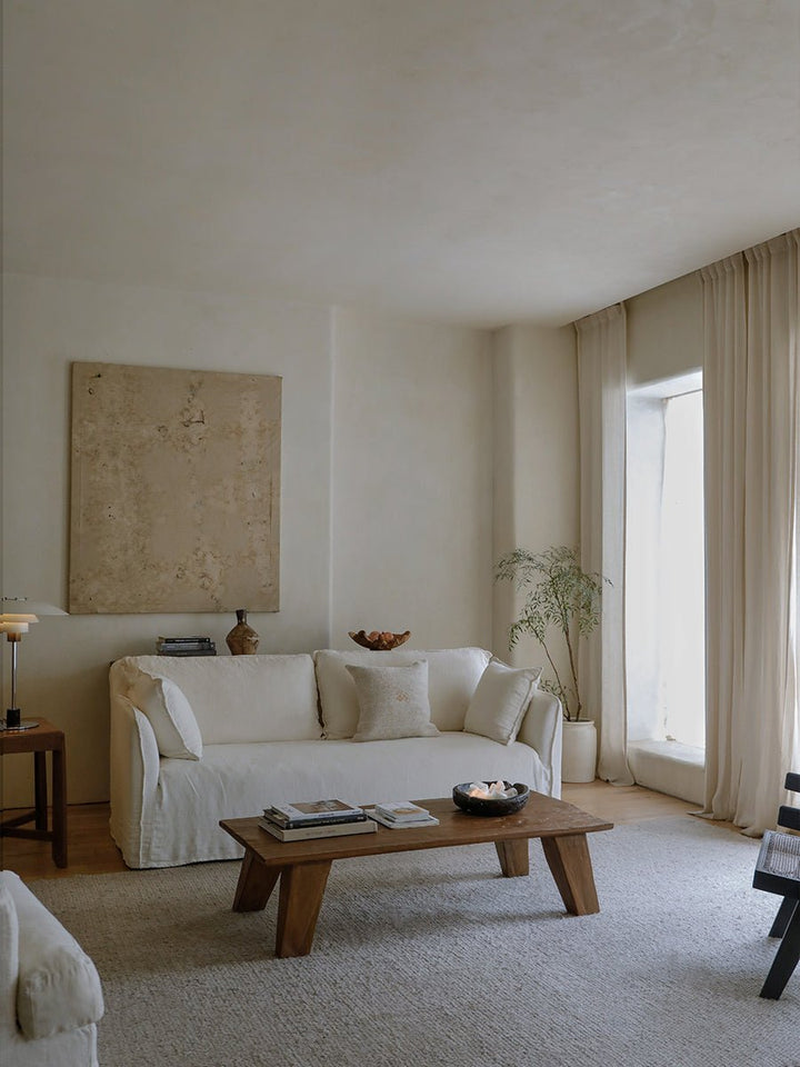 Stylish living room with white sofa, wooden coffee table, and decorative plants.