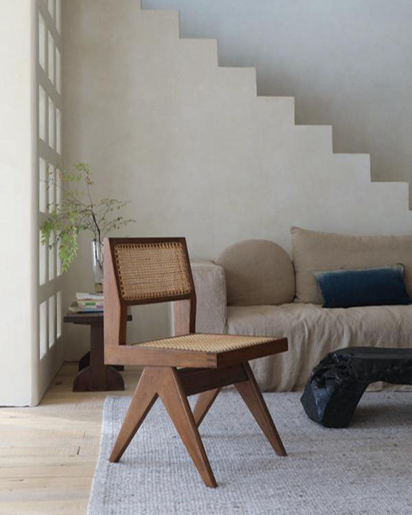 Chandigarh armless chair in teak wood and rattan, styled in a modern living room.