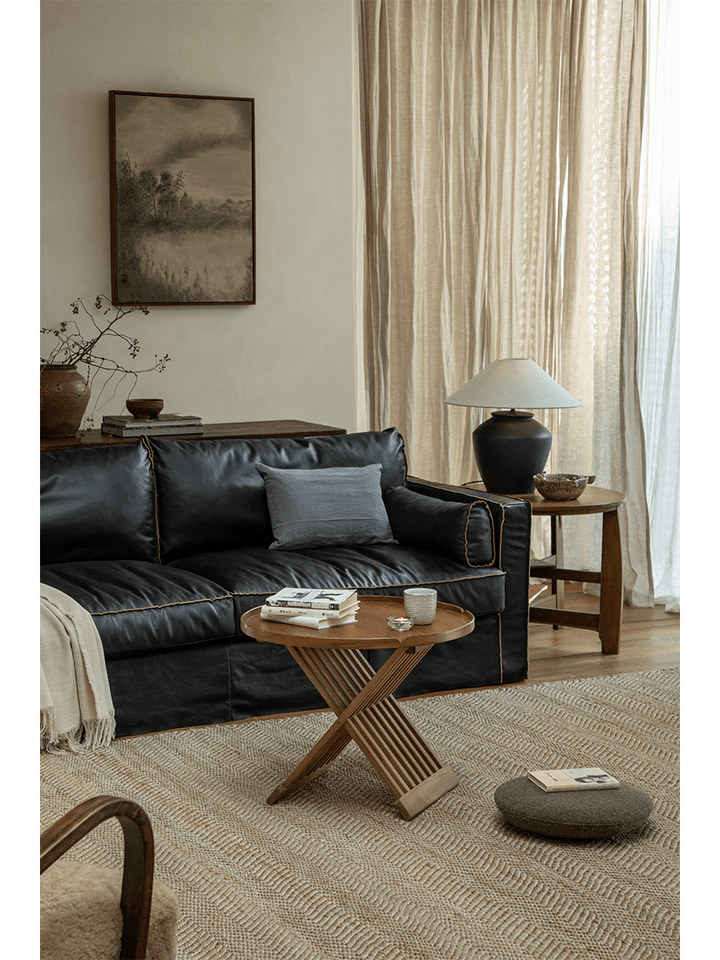Cozy living room with a round teak folding coffee table and black sofa.