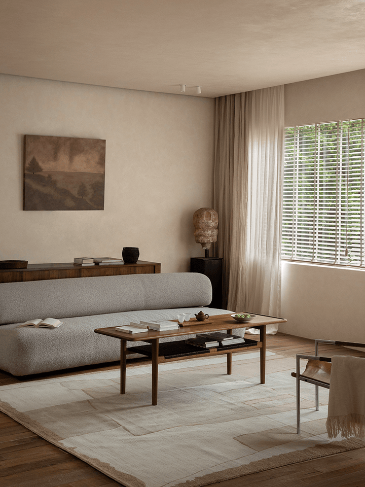 Light wooden coffee table in modern living room with art and natural light.