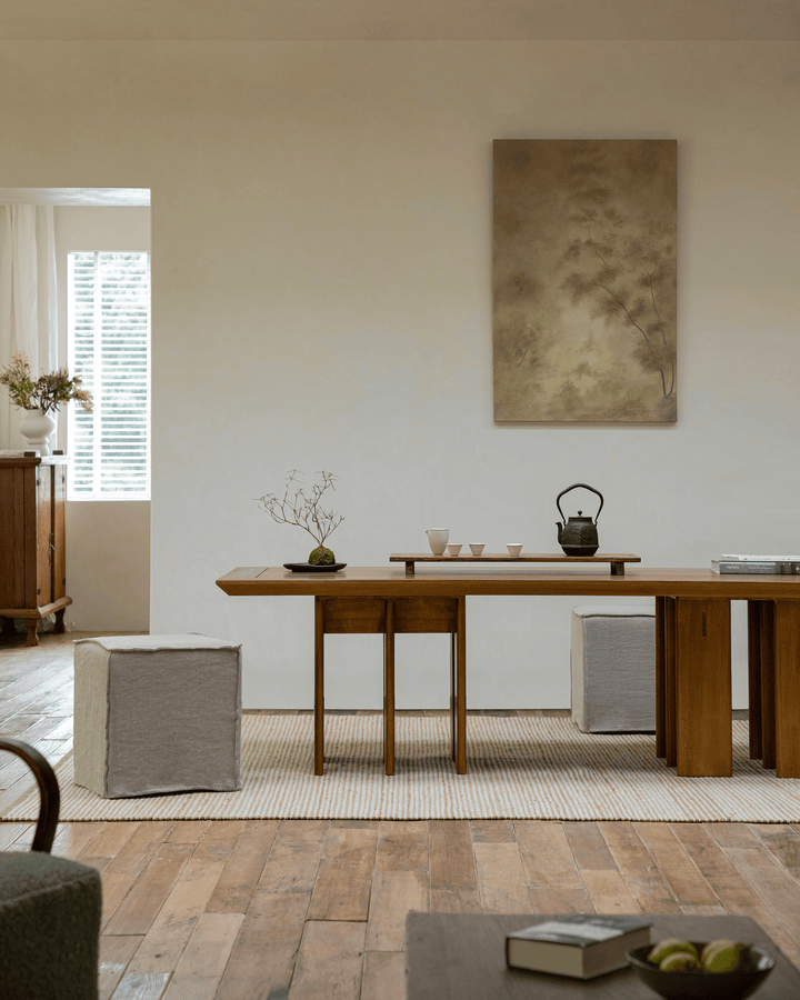 Minimalist wooden dining area with tea set and two elegant tables in soft natural light.