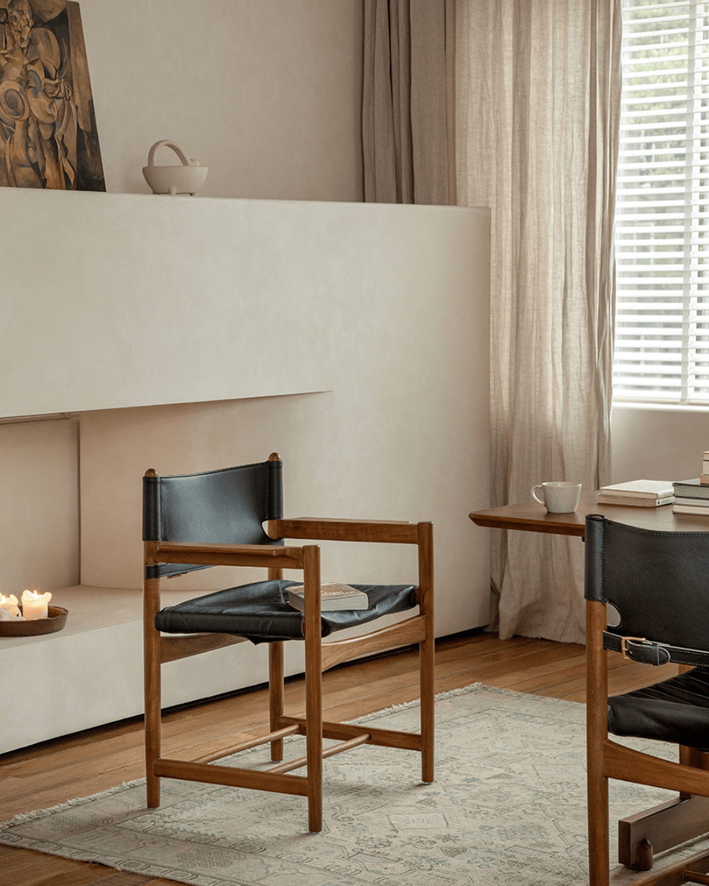 Spanish Dining Chair with black leather seat and teak wood frame in a neutral, cozy dining room setting