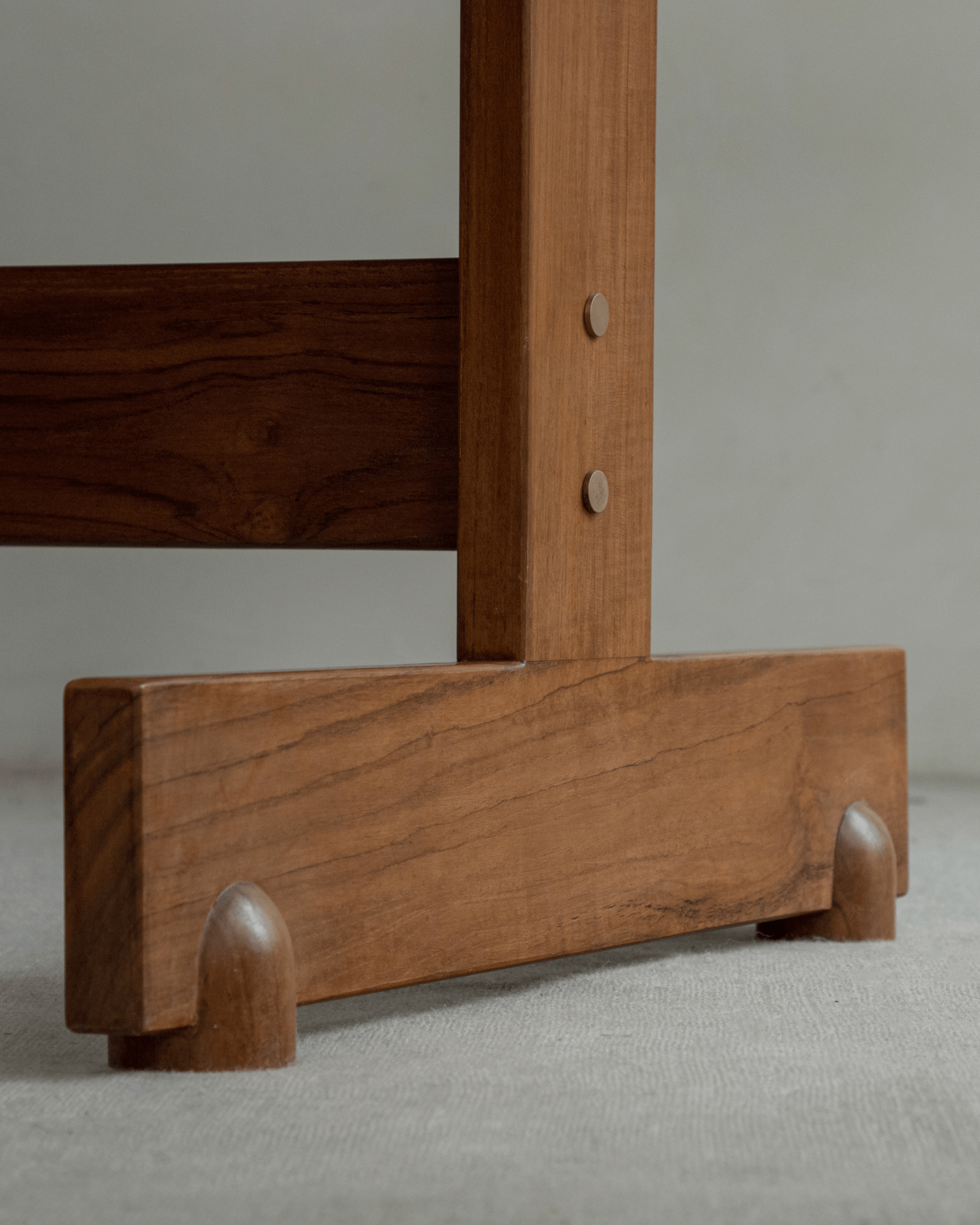 Close-up of Hoof Dining Table's I-shaped base and legs. Solid, warm brown wood construction.
