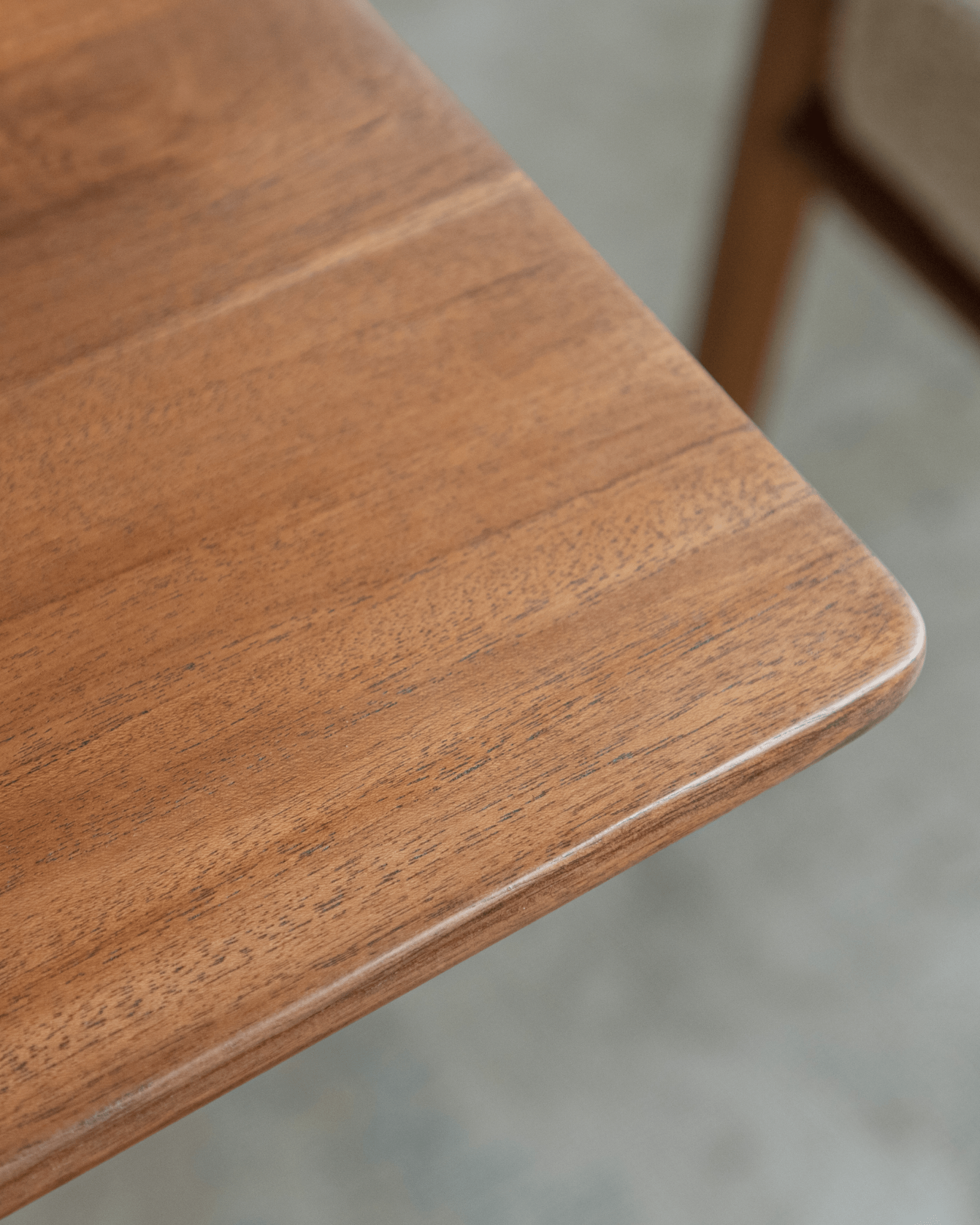 Hoof Dining Table detail: warm brown solid wood tabletop, showcasing the wood grain and elegant design.