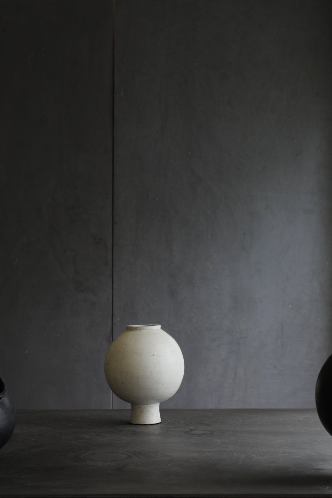 Off-white ceramic sphere vase with short base. Minimalist design for home decor.