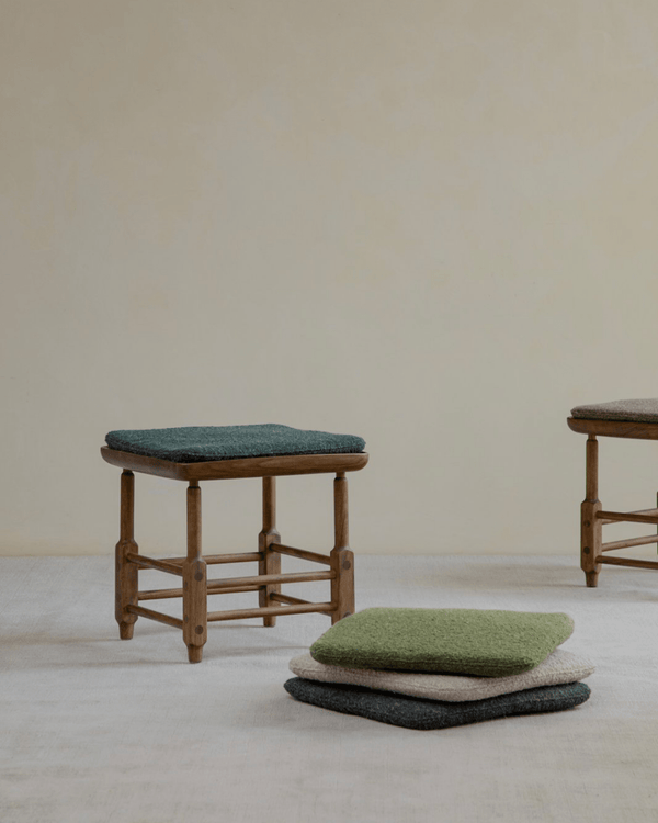 Magrini Stool in zebrawood with green cushion and other color cushions on the floor, interior design