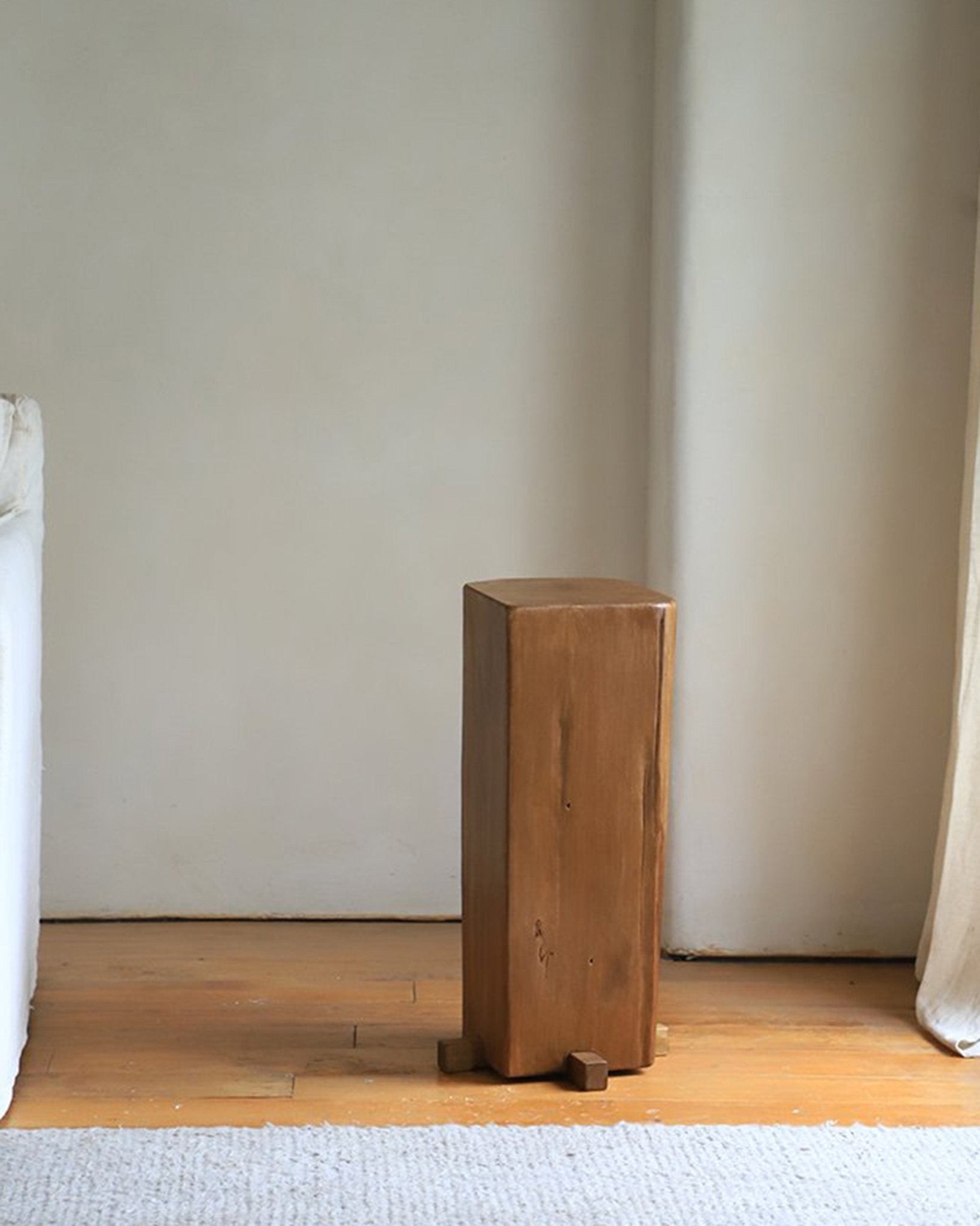 Rustic wooden pedestal with natural aged texture, showcasing timeless simplicity in an organic interior setting.