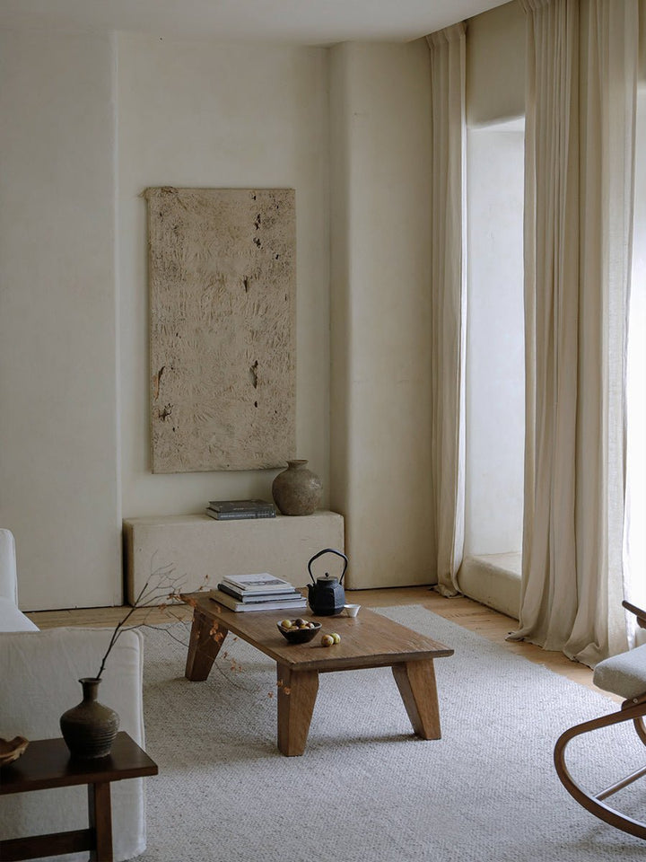 Minimalist living room with wooden coffee table, white sofa, and natural decor.
