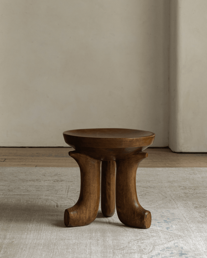 Quincy stool with curved wooden legs in minimalist interior design.