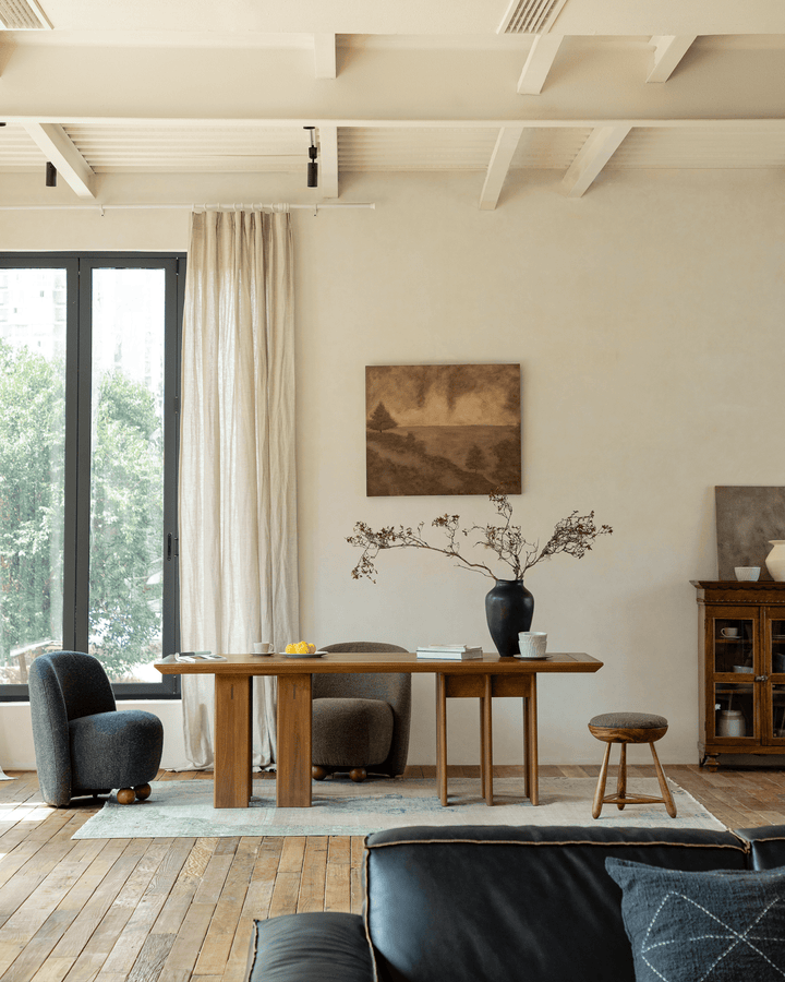 Stylish wooden dining table with two modern chairs and decorative vase in bright room.