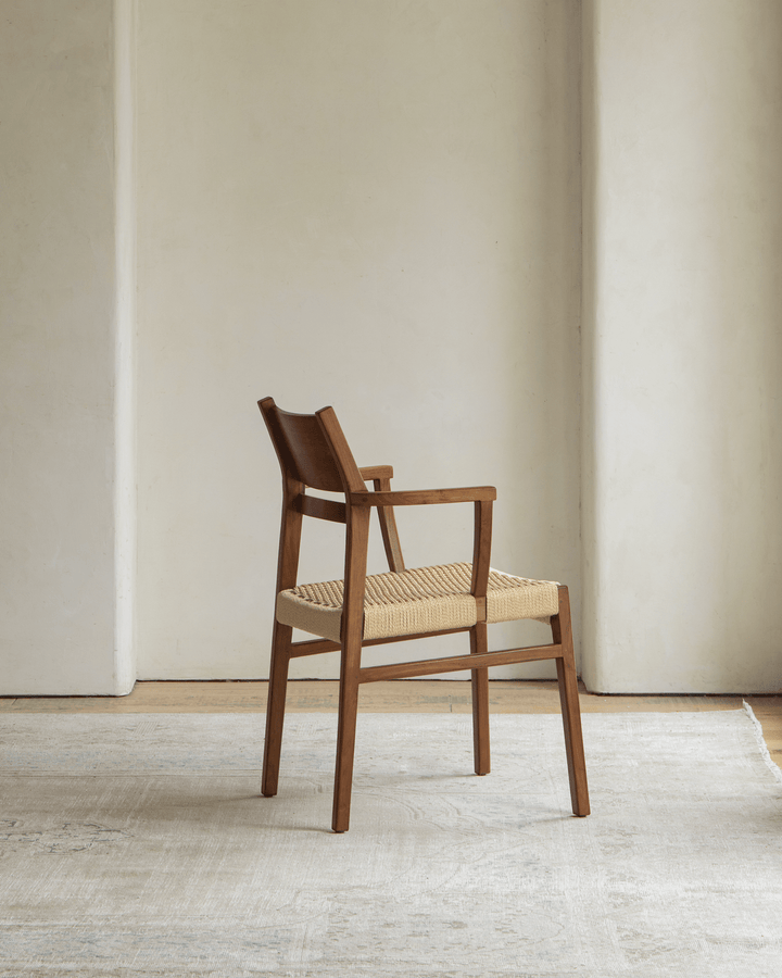 Hug Chair with wooden frame and woven seat positioned in a minimalist room.