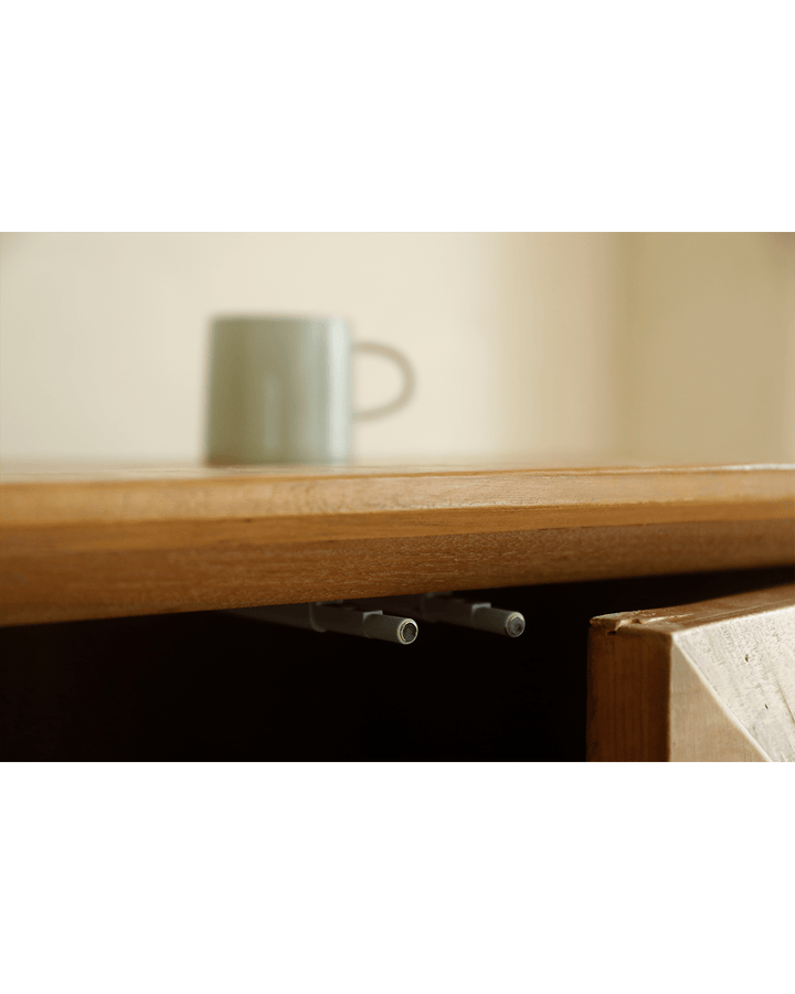 Close-up of Bumpy Sideboard's top with a cup and sleek detail.