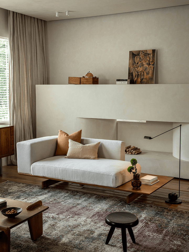 Modern linen modular sofa with orange cushions in a cozy minimalist living room.
