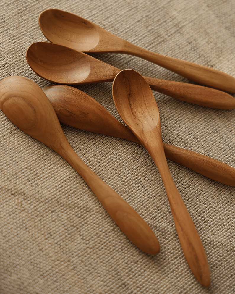 Four wooden table spoons made of natural wood on beige linen fabric