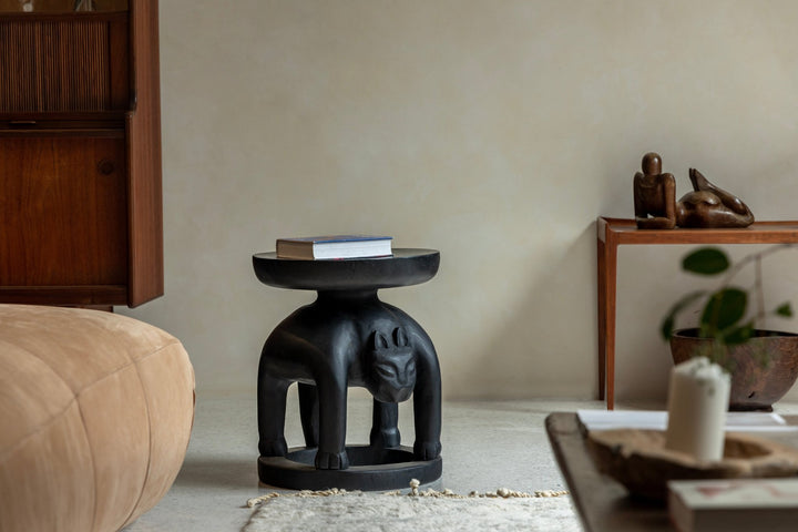 Panther-shaped wooden Tribal Sculptural End Table with book, enhancing modern living room decor.