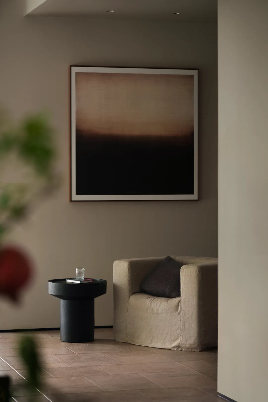 Modern interior with a framed abstract painting on a wall, a chair, and a small table.