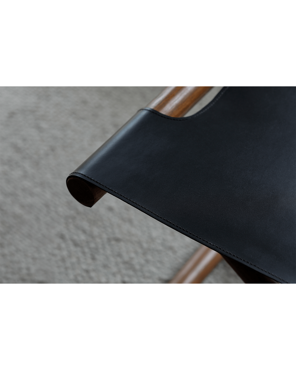 Lux Leather Stool detail: Black saddle leather seat and teak wood frame, showcasing quality craftsmanship and materials