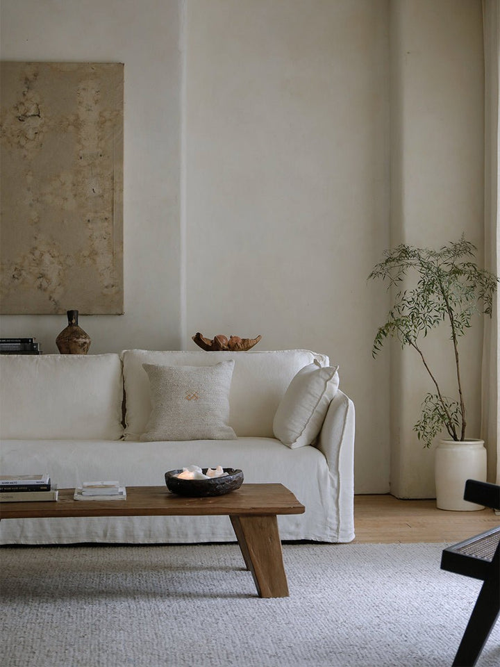 Serene living room with white sofa, wooden coffee table, and minimalist decor.