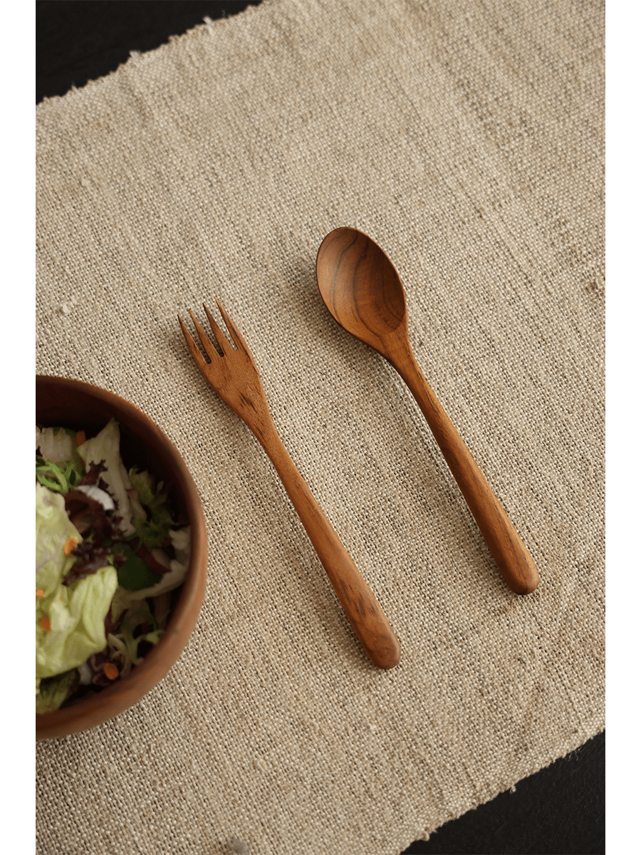 Wooden spoon and fork set with salad bowl on linen fabric, natural wood finish, product shot