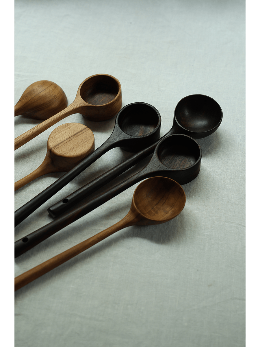 Teak coffee spoons, different shades of brown and black, elegant design on a linen surface.