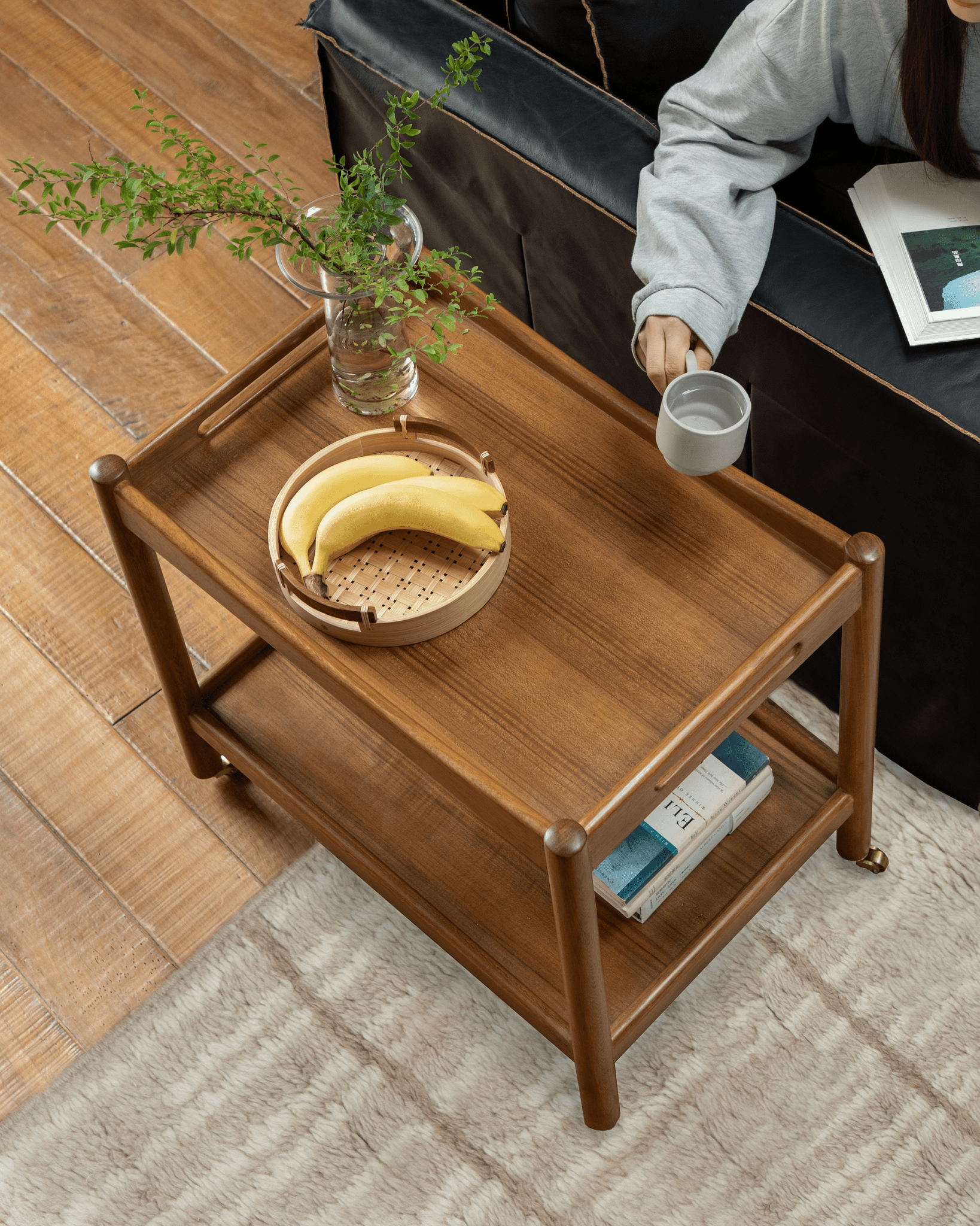 Brooklyn Bar Cart styled with a tray of bananas, vase with greenery, and a cup.  A cozy living room setting with the cart.