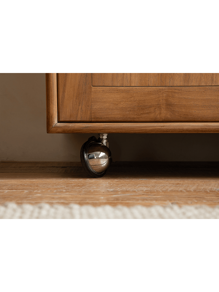 Close-up of stylish wheel on teak wood display cabinet for easy movement.