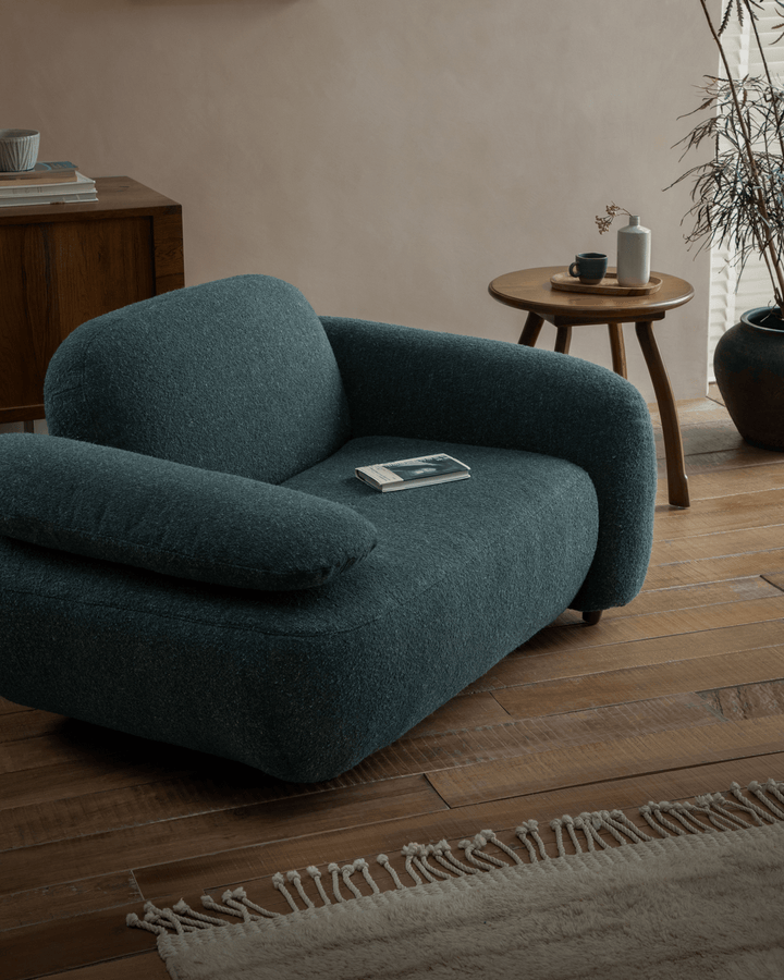Teal Gestein Bouclé Armchair with soft cushions in stylish living room with wooden decor.