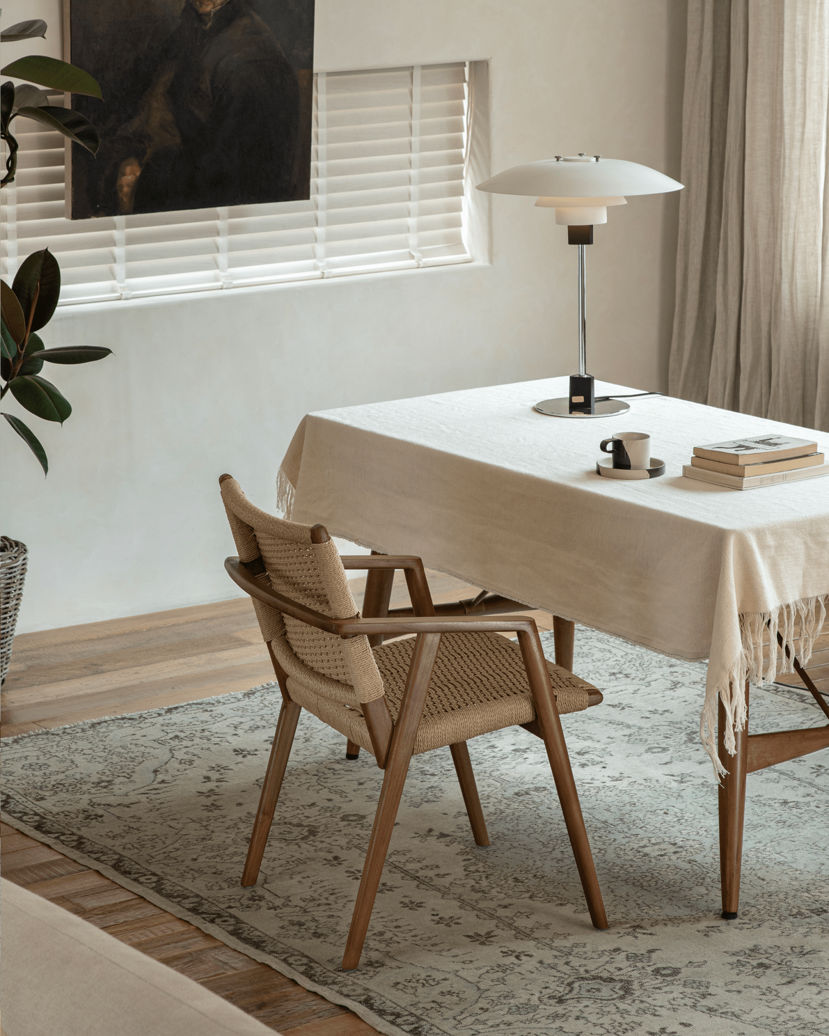 Louisa Chair in a dining setting. Teak frame and woven seat, showcasing Mid-Century Modern design, natural light and rugs