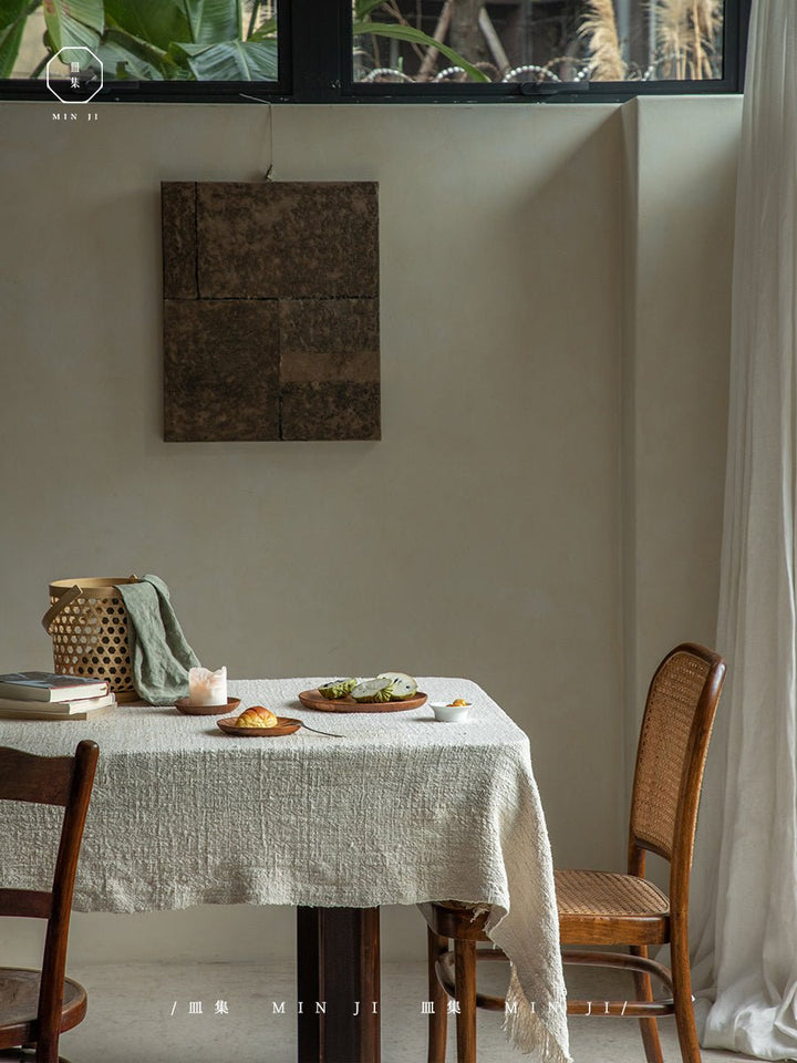 Teak wood dining plates and bowls arranged on a textured tablecloth with pastries.