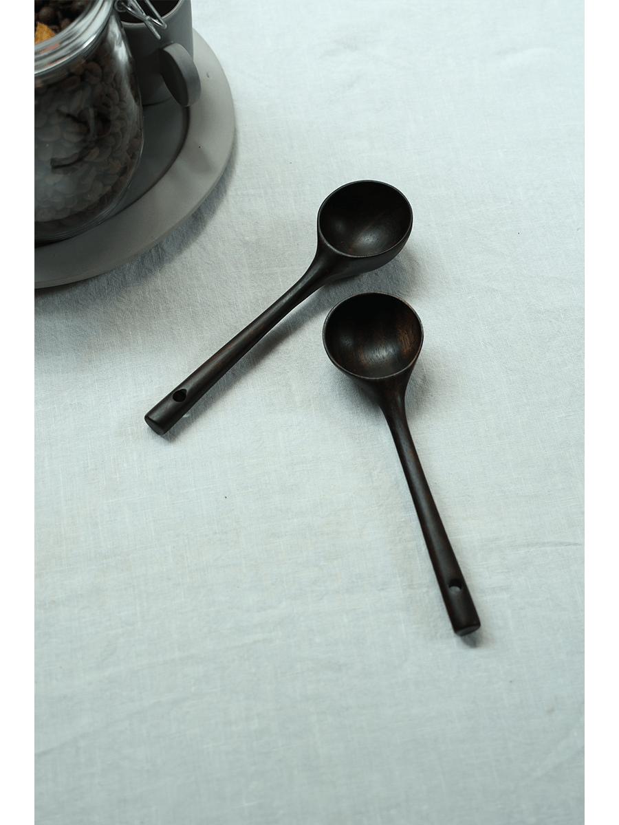 Teak coffee spoons, dark brown color, on white linen surface for coffee serving.